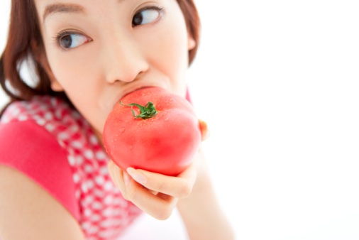 Young woman eating a tomato